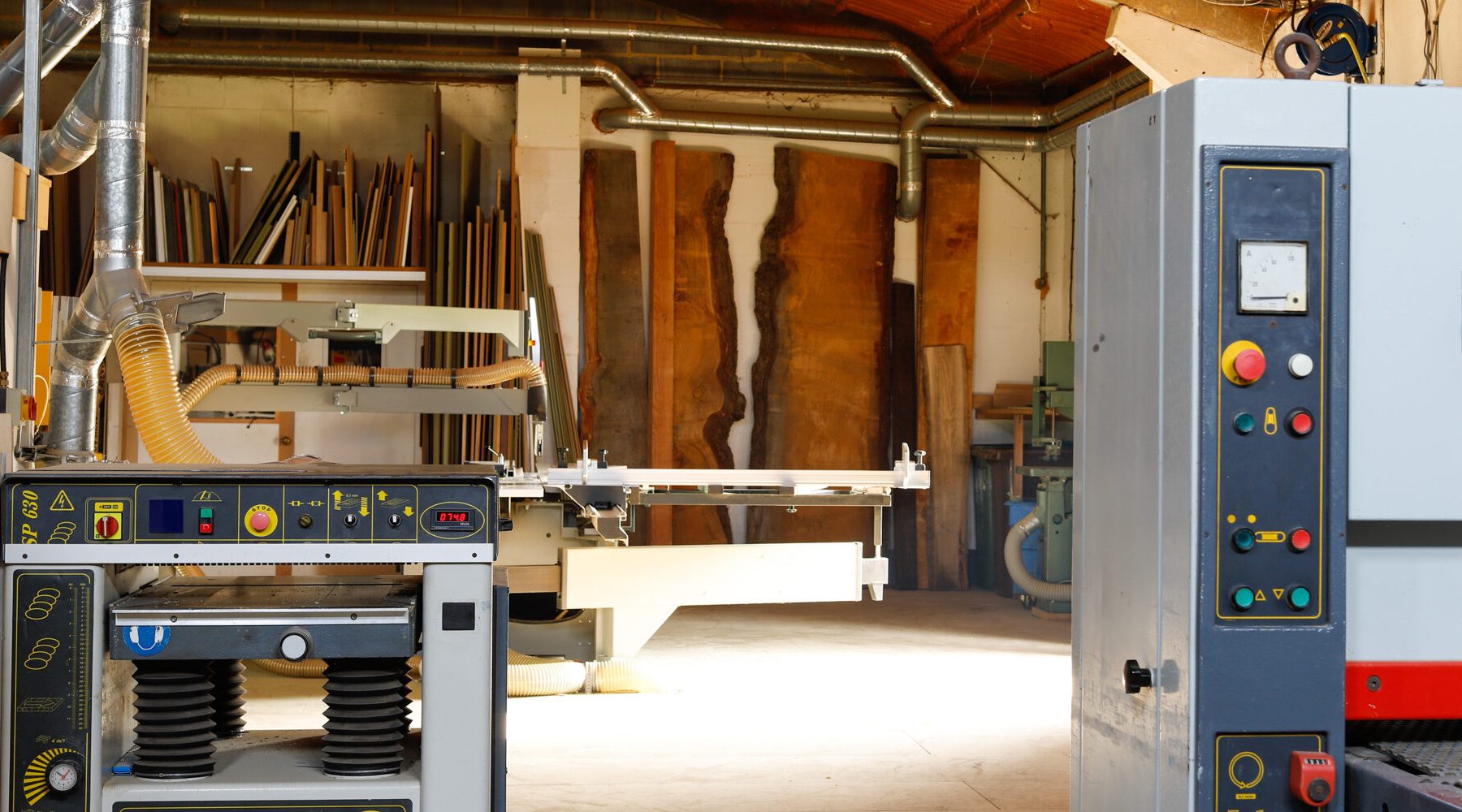 Workshop view showing machinery and huge slabs of timber against the wall